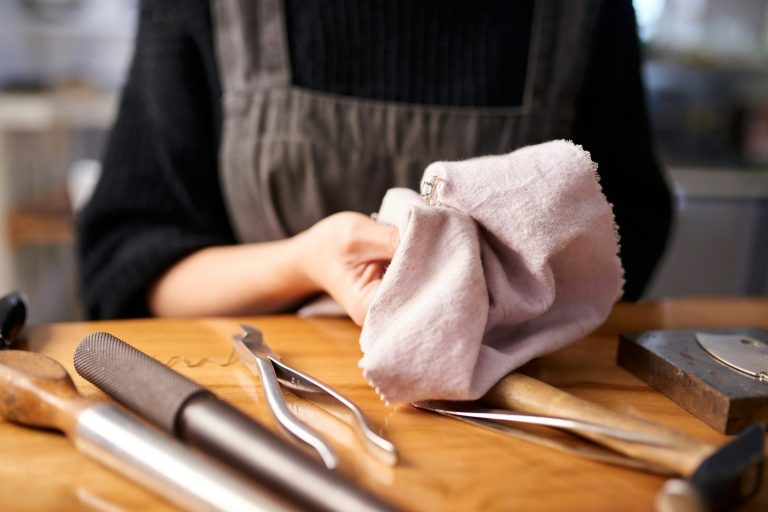 Eine Person hält ein Handtuch, umgeben von Reinigungsutensilien auf einem Tisch.
