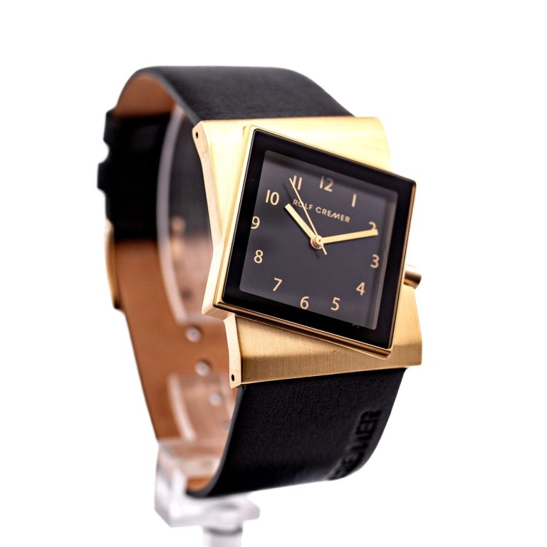 Schwarze Uhr mit quadratischem Ziffernblatt und goldfarbenem Gehäuse.