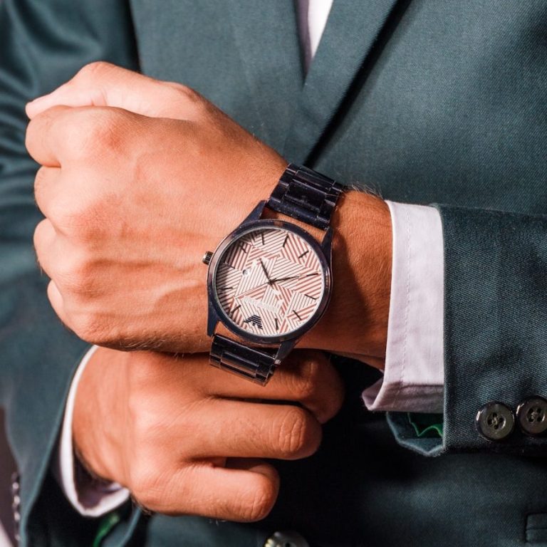 Elegante Armbanduhr an einem Handgelenk, das einen Anzugärm hält.